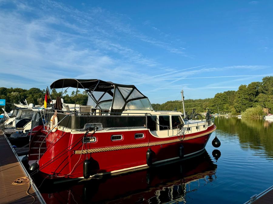 Rot-weiße Motoryacht am Steg bei strahlend blauem Himmel